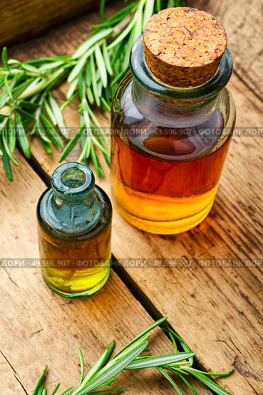 Essential oil bottle with fresh rosemary. Bottle glass of essential rosemary extract. Rosemary in herbal medicine. Стоковое фото, агентство Ingram Publishing / Фотобанк Лори