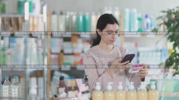 European woman uses mobile phone to scan the barcode on a box of paracetamol. Buyer at the pharmacy pays for medicines and pills with to qr code. Стоковое видео, видеограф Яков Филимонов / Фотобанк Лори