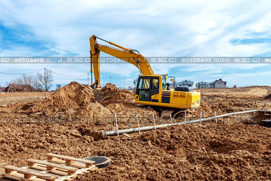 Excavator dig the trenches at a construction site. Trench for laying external sewer pipes. Sewage drainage system for a multi-story building. Digging the pit foundation. Стоковое фото, фотограф Дмитрий Головач / Фотобанк Лори