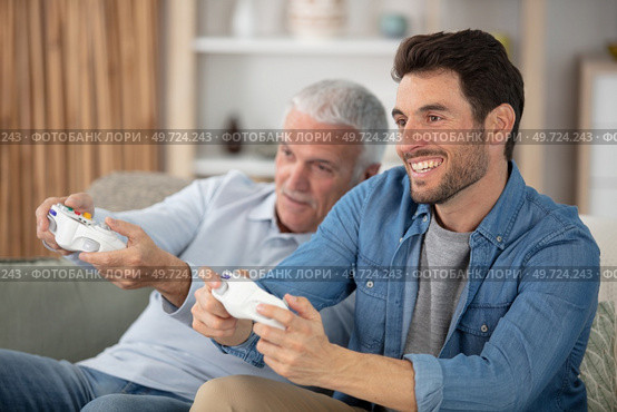excited millennial man and senior father playing videogames. Стоковое фото, агентство Ingram Publishing / Фотобанк Лори