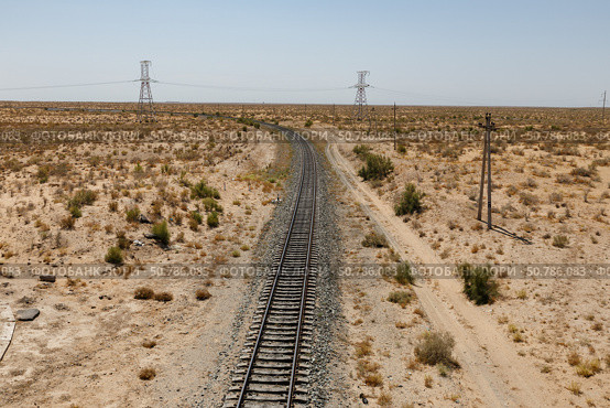Expansive view of a winding railway through arid desert landscape with power lines nearby. Uzbekistan. Стоковое фото, фотограф Михаил Пряхин / Фотобанк Лори