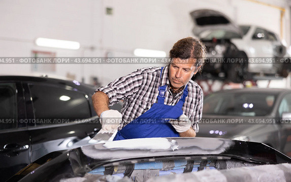 Experienced auto body technician puttying damaged car bumper. Стоковое фото, фотограф Яков Филимонов / Фотобанк Лори