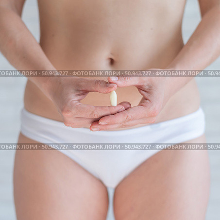 Faceless Caucasian woman in white panties and with a bare belly holds a healing candle. Girl demonstrates anal or vaginal suppository. Prescription from a gynecologist for women's health. Стоковое фото, фотограф Михаил Решетников / Фотобанк Лори