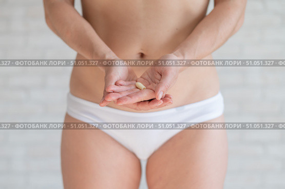 Faceless Caucasian woman in white panties and with a bare belly holds a healing candle. Girl demonstrates anal or vaginal suppository. Prescription from a gynecologist for women's health. Стоковое фото, фотограф Михаил Решетников / Фотобанк Лори