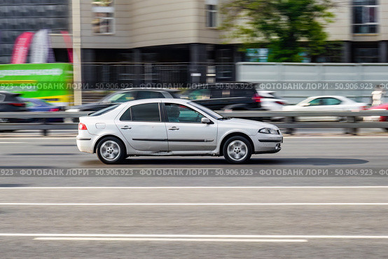 Facelifted Renault Laguna II at the city road in motion. Silver car driving along the street in city, side view. Accelerating with low-emission. Редакционное фото, фотограф Константин Григорьев / Фотобанк Лори
