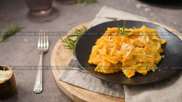Farfalle pasta with pumpkin sauce in a ceramic plate on a dark stone kitchen counter top. Стоковое фото, агентство Ingram Publishing / Фотобанк Лори