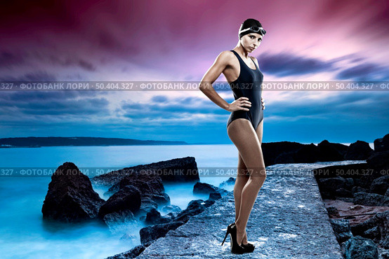 Fashion swimmer woman with googles and swimming cap in high hells, with a beach on the background. Стоковое фото, агентство Ingram Publishing / Фотобанк Лори