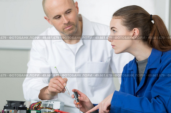 female apprentice repairing electrical appliance under supervision. Стоковое фото, агентство Ingram Publishing / Фотобанк Лори