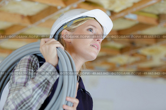 female builder carrying cable on her shoulder. Стоковое фото, агентство Ingram Publishing / Фотобанк Лори