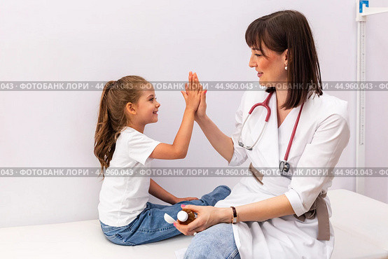 Female children's doctor gives high five to little patient after checkup in clinic, encourage her before procedure, congratulate successful treatment or with good health test results. Стоковое фото, фотограф Ирина Михайличенко / Фотобанк Лори