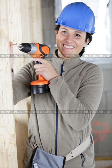female construction worker having driller tool drilling wall. Стоковое фото, агентство Ingram Publishing / Фотобанк Лори