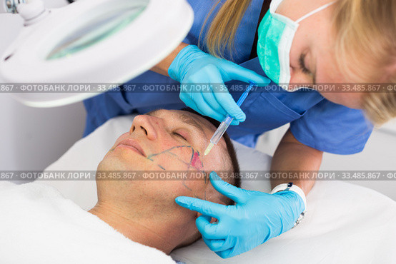 Female doctor is doing injection to patient in skin of face. Стоковое фото, фотограф Яков Филимонов / Фотобанк Лори