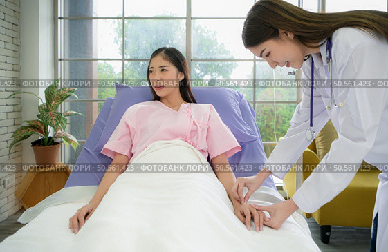 Female doctor with IV equipment will give IV fluids and examine patients lying in hospital beds. Стоковое фото, агентство Ingram Publishing / Фотобанк Лори