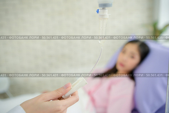 Female doctor with IV equipment will give IV fluids and examine patients lying in hospital beds. Стоковое фото, агентство Ingram Publishing / Фотобанк Лори