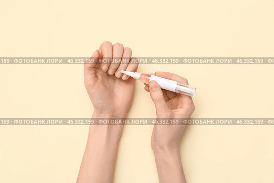 Female hands applying cuticle oil with pen on beige background. Стоковое фото, фотограф Pixel_shot / Фотобанк Лори