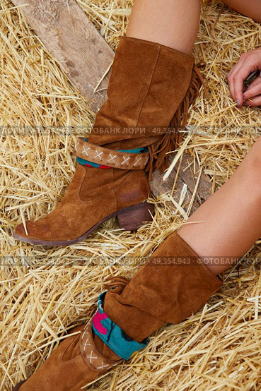 female legs with leather brown on straw bale. female legs with leather brown boots relaxed on straw bale barn. Стоковое фото, агентство Ingram Publishing / Фотобанк Лори