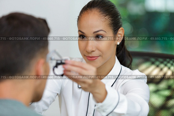 female optician placing testing frames onto male patient. Стоковое фото, агентство Ingram Publishing / Фотобанк Лори