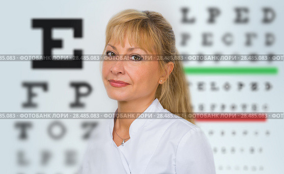 Female optician standing in front of eyesight test at hospital. Стоковое фото, фотограф Kirill Kedrinskiy / Ingram Publishing / Фотобанк Лори