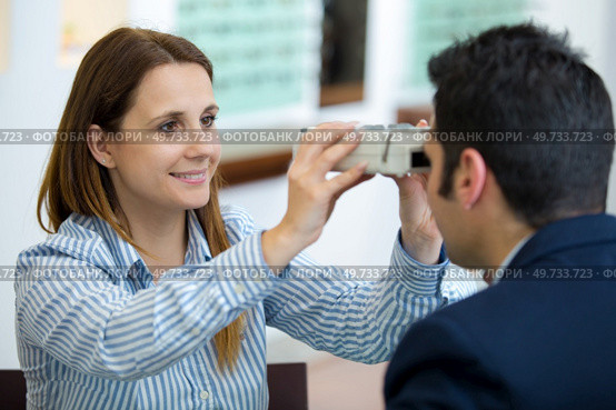 female optometrist examines eyesight of young male patient. Стоковое фото, агентство Ingram Publishing / Фотобанк Лори
