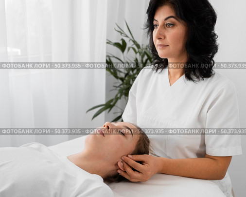 female osteopathist treating patient indoors. Стоковое фото, агентство Ingram Publishing / Фотобанк Лори