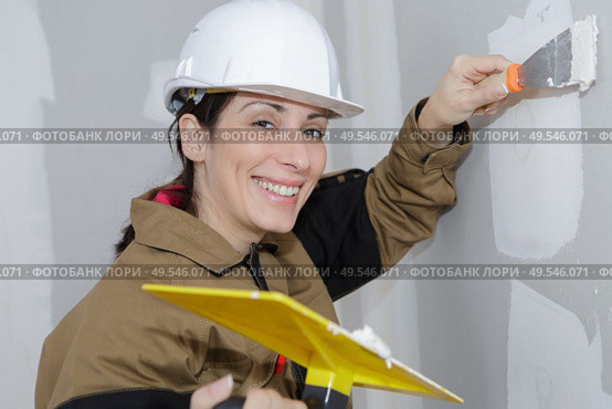 female plasterer painter doing a wall renovation. Стоковое фото, агентство Ingram Publishing / Фотобанк Лори
