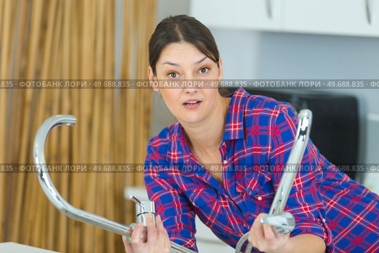 female plumber fixing tap with adjustable wrench. Стоковое фото, агентство Ingram Publishing / Фотобанк Лори