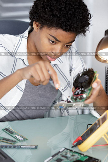 female repairwoman disassembling smartphone with screwdriver. Стоковое фото, агентство Ingram Publishing / Фотобанк Лори