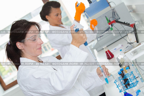 female scientists using pipettes in lab. Стоковое фото, агентство Ingram Publishing / Фотобанк Лори