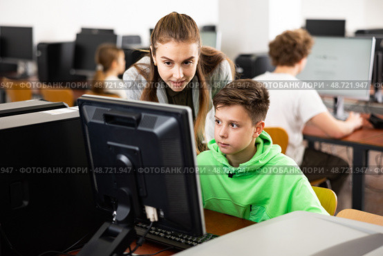 Female teacher consulting tween boy studying in computer class. Стоковое фото, фотограф Яков Филимонов / Фотобанк Лори