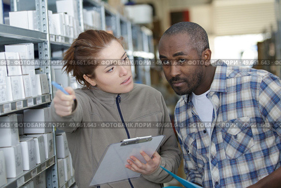 female warehouse staffadvising colleague by pointing forwards. Стоковое фото, агентство Ingram Publishing / Фотобанк Лори