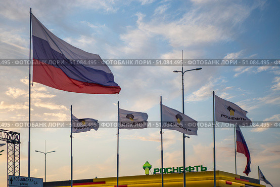 Флаг России и компании Роснефть на  фоне закатного неба. Редакционное фото, фотограф Литвяк Игорь / Фотобанк Лори