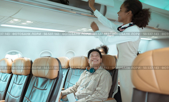 Flight attendant check the order of the passenger’s luggage storage. Стоковое фото, агентство Ingram Publishing / Фотобанк Лори