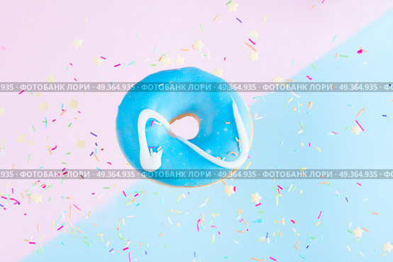 flying doughnuts on blue. one sweet doughnut with sprinkles on blue and pink abstract background with copy space. Стоковое фото, агентство Ingram Publishing / Фотобанк Лори