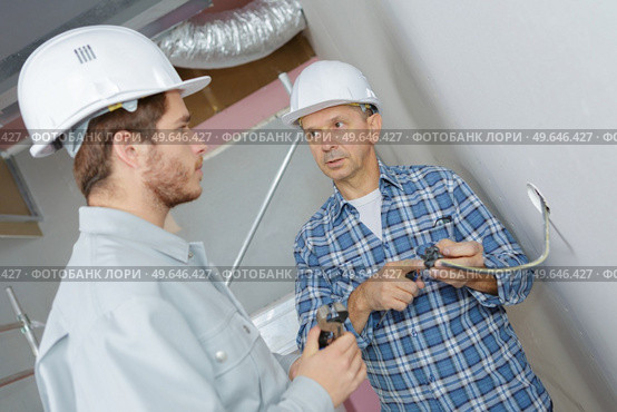 foreman showing dismantled socket to eapprentice electrician. Стоковое фото, агентство Ingram Publishing / Фотобанк Лори
