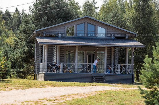 Frame house in Scandinavian style. The landscape. Quiet rest. The concept of glamping and chalet rentals. Wooden house with a veranda in nature. (2024 год). Стоковое фото, фотограф Photojuli / Фотобанк Лори