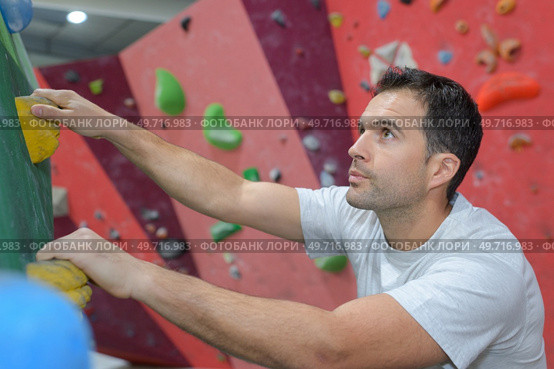 free climber young man climbing artificial boulder in gym. Стоковое фото, агентство Ingram Publishing / Фотобанк Лори