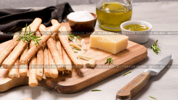 Fresh baked homemade grissini bread sticks in vintage metal grid box with olive oil and rosemary herbs over kitchen counter top. Стоковое фото, агентство Ingram Publishing / Фотобанк Лори