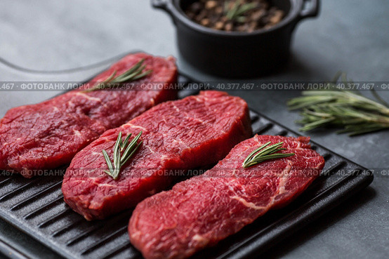 Fresh meat. Raw beef steaks with rosemary and spices on a stylish blackboard. Flat top view. Стоковое фото, фотограф Photojuli / Фотобанк Лори