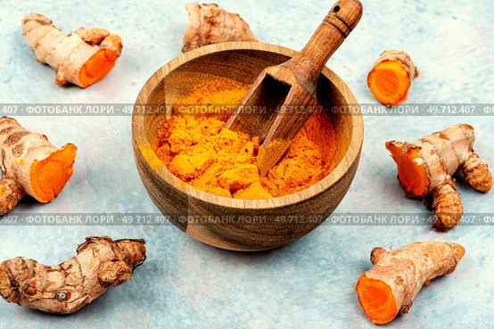 Fresh turmeric root in wooden bowl and turmeric powder. Curcuma longa Linn.. Turmeric root and curcuma powder, medicine herb. Стоковое фото, агентство Ingram Publishing / Фотобанк Лори