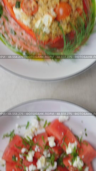 Fresh watermelon salad combining crumbled feta, chopped chives alongside bulgur stuffed bell peppers featuring tomatoes, dill, complemented by pine nuts, cranberry garnish. Стоковое видео, видеограф Данил Руденко / Фотобанк Лори