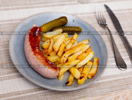 Fried small sausage and french fries, completed with pickled gherkin cucumber. Стоковое фото, фотограф Яков Филимонов / Фотобанк Лори