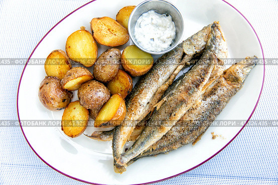 Fried smelt with boiled potatoes and mushroom sauce on a white plate. Delicious rustic lunch. Стоковое фото, фотограф Евгений Ткачёв / Фотобанк Лори