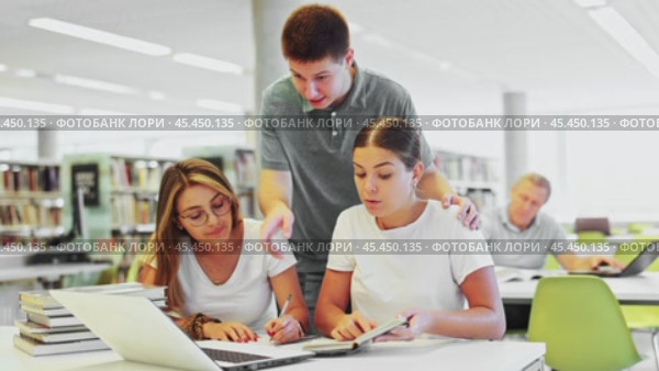 Friendly happy group of students preparing together for exam in modern university library. Стоковое видео, видеограф Яков Филимонов / Фотобанк Лори