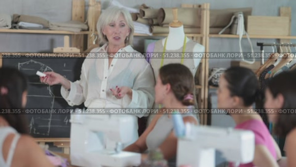 Friendly old instructor explaining key points of clothing design during sewing lesson. Стоковое видео, видеограф Яков Филимонов / Фотобанк Лори