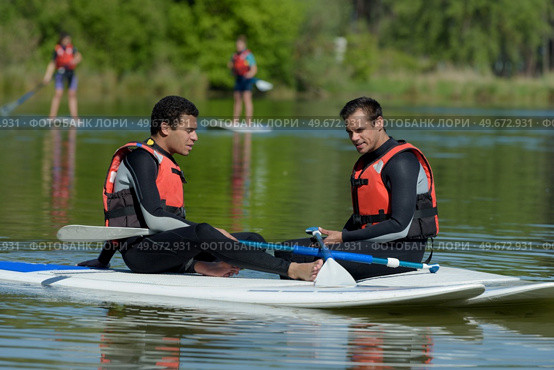 friends chating on stand up paddleboarding. Редакционное фото, агентство Ingram Publishing / Фотобанк Лори