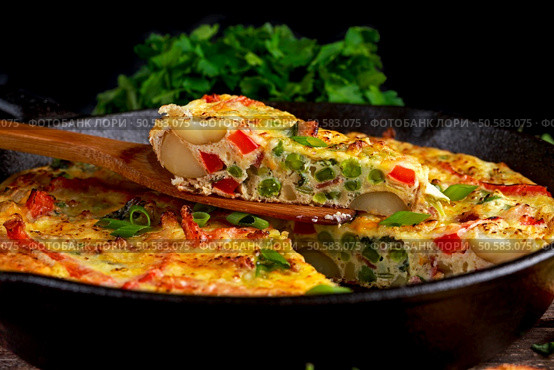 Frittata made of eggs, potato, bacon, paprika, parsley, green peas, onion, cheese in iron pan on wooden table. Frittata made of eggs, potato, bacon, paprika, parsley, green peas, onion, cheese in iron pan. on wooden table. Стоковое фото, агентство Ingram Publishing / Фотобанк Лори