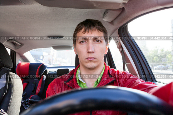 Front view at male driver sitting close to steering wheel in car, man driving a vehicle. Стоковое фото, фотограф Кекяляйнен Андрей / Фотобанк Лори