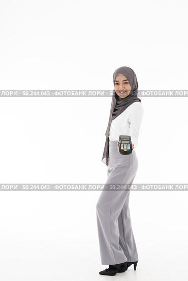 Full body portrait of Confident happy smiling female muslim woman with EDC machine as owner merchant concept. Studio shot on white background. Using for sale consumerism and shopaholic concept. Стоковое фото, агентство Ingram Publishing / Фотобанк Лори