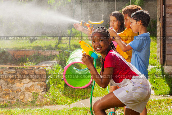 Girl and friends in water gun fight wet fun game. Стоковое фото, фотограф Сергей Новиков / Фотобанк Лори