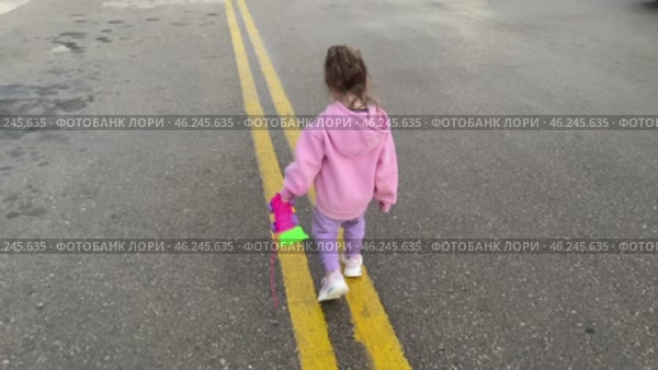 Girl child toddler walking outside in puddles on cloudy day. Стоковое видео, видеограф Spirit River / Фотобанк Лори